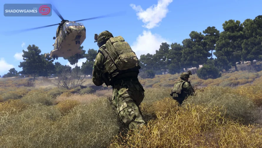 سربازان استتار پوش در حال پیشروی در علفزار کنار هلیکوپتر در بازی آنلاین Arma 3